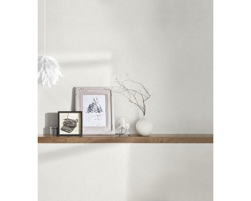 Obývací pokoj s tapetou, policí a dekorativními prvky, jako jsou rámečky a váza