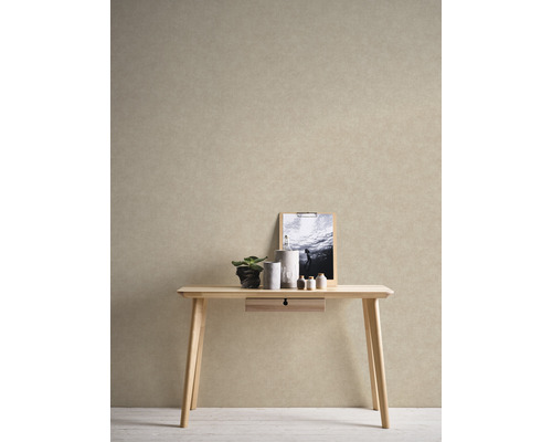 Dekorativní scéna se světlým dřevěným stolem, rostlinou, svíčkami a obrázkem na zdi