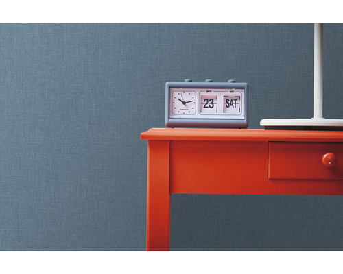 Scéna s šedým kalendářem na červeném stole před strukturovanou stěnou