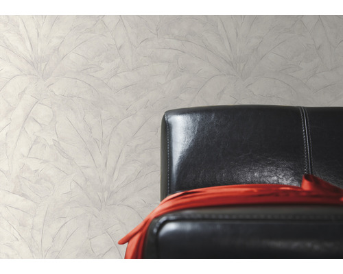 Nástěnná dekorace s motivem listů vedle černého koženého křesla