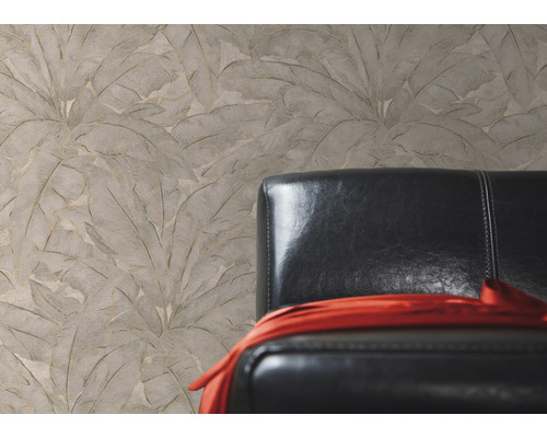 Béžová strukturovaná tapeta s motivem listů vedle černého koženého křesla