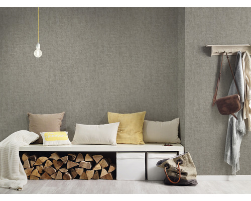 Obývací pokoj s šedou textilní tapetou, lavice s polštáři, polena a úložné boxy