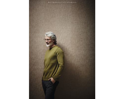 Muž v svetru stojí před stěnou s tapetou z kolekce Metropolitan Stories