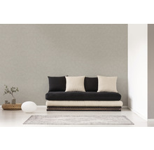 Světlá místnost s pohovkou, několika polštáři, malým stolem, lampou a kobercem.