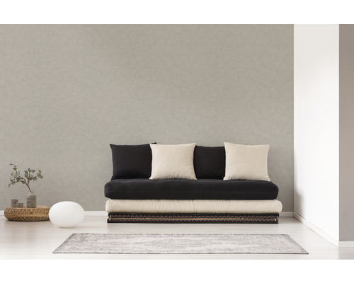 Světlá místnost s pohovkou, několika polštáři, malým stolem, lampou a kobercem.