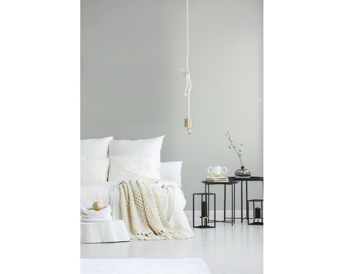 Světle zařízená ložnice s postelí, příručními stolky a lampou