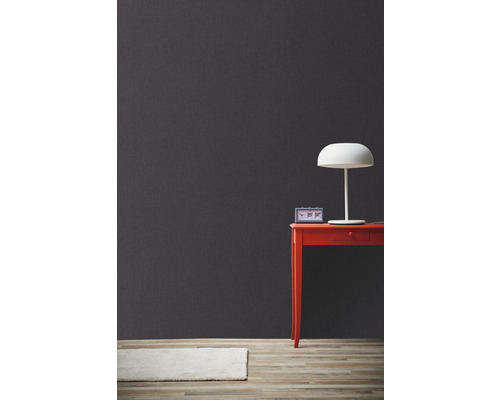 Dekorativní šedá stěna se stolem, lampou a kobercem pro moderní obytné prostředí.