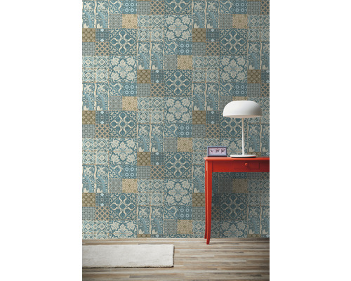 Pohled na pokoj s tapetou se vzorem, červeným stolem a lampou