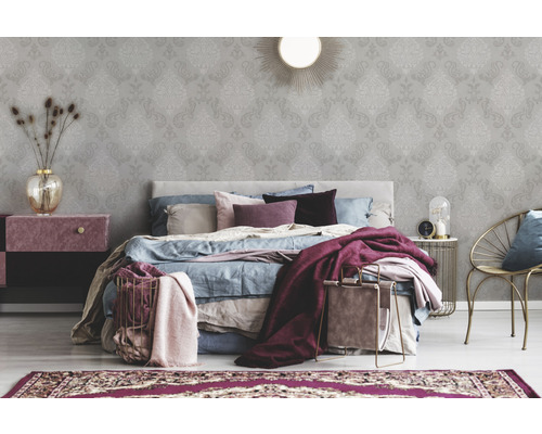 Ložnice s tapetou s ornamentálním vzorem, postelí a odkládacím stolkem