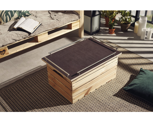 Dřevěná bedna jako konferenční stolek s deskou a kovovými madly v obývacím pokoji.