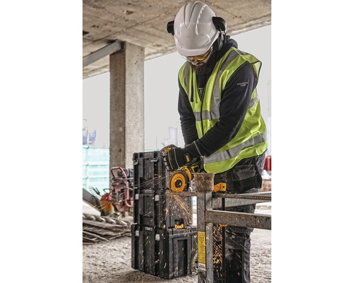 "Pracovník s ochrannou přilbou a brýlemi řeže úhlovou bruskou kus kovu