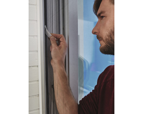 Muž montuje síť proti hmyzu na okno