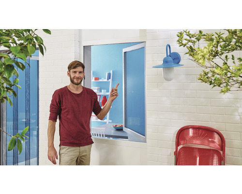 Muž ukazuje na okenní síť proti hmyzu v obytné oblasti