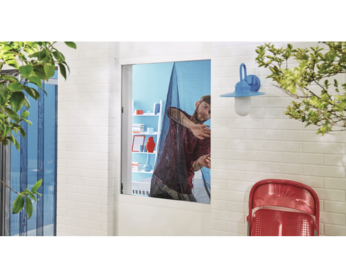 Muž montuje síť proti hmyzu na okno pro ochranu proti hmyzu.