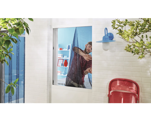 Muž připevňuje do okna síť proti hmyzu.