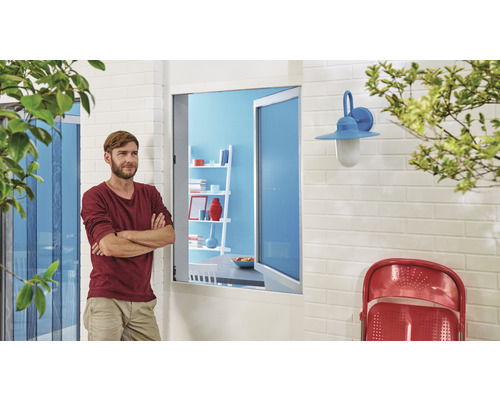 Muž před terasovými dveřmi se sítí proti hmyzu, nástěnným světlem a židlí