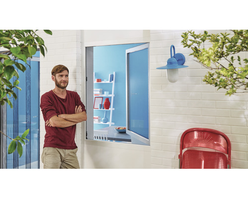 Vnější pohled na dům se sítí proti hmyzu, oknem, nástěnnou lampou a mužem