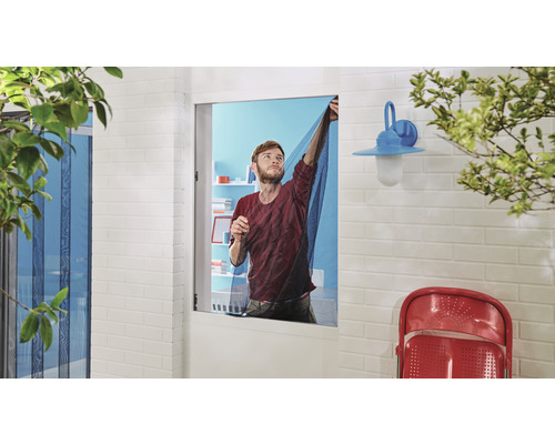 Muž upevňuje síť proti hmyzu na okno.