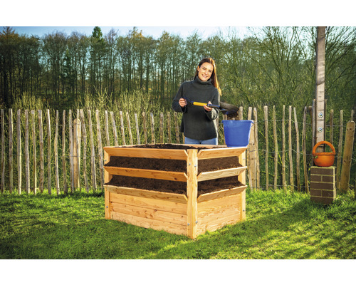 Dřevěný vyvýšený záhon se třemi úrovněmi a ženou, která přidává zeminu.