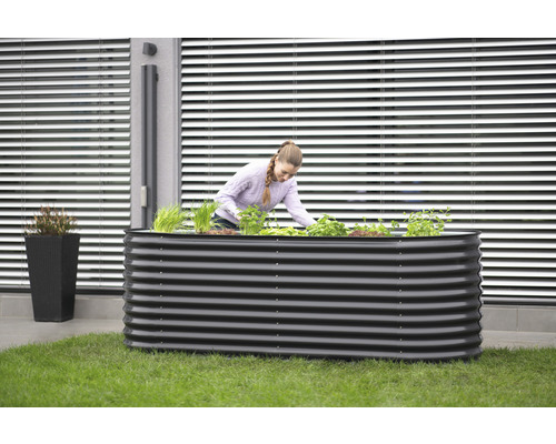 Kovový vyvýšený záhon s ženou, která sází na zahradě