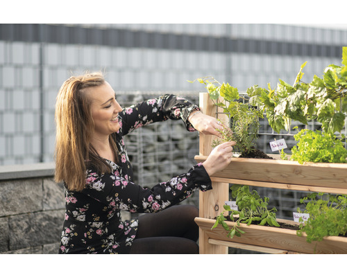 Žena pečuje o bylinky v dřevěném bylinkovém regálu do zahrady