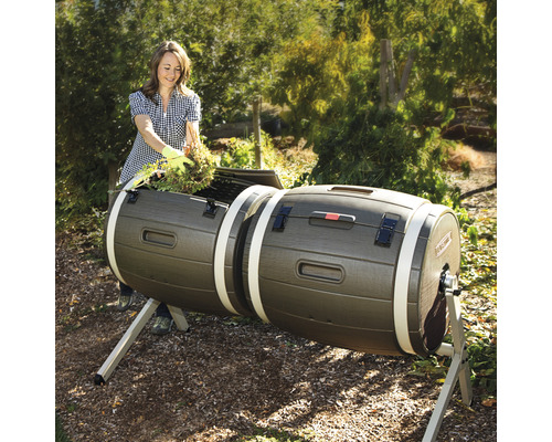 Žena plní zahradním odpadem dvojitý kompostér na zahradě.