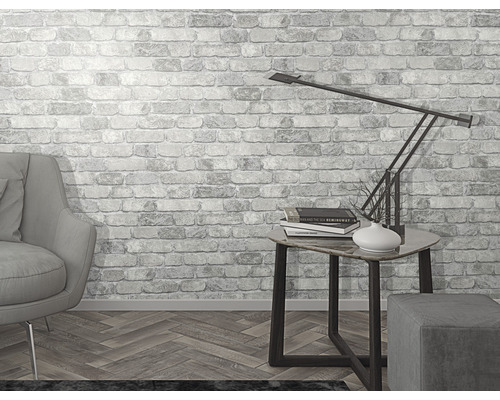 Světlá místnost s křeslem, stolní lampou a tapetou s motivem zdiva