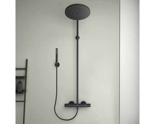 Černá sprchová armatura s hlavovou a ruční sprchou namontovaná na stěně.
