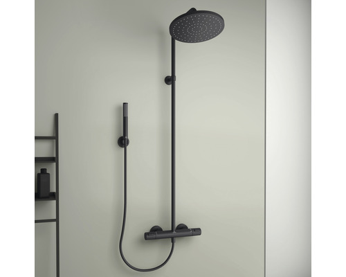 Černá sprchová armatura s hlavovou a ruční sprchou namontovanou na zdi.