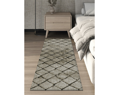 Koberec s kosočtvercovým vzorem v ložnici vedle postele a nočního stolku