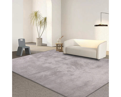 Světlý obývací pokoj s kobercem, pohovkou a židlí