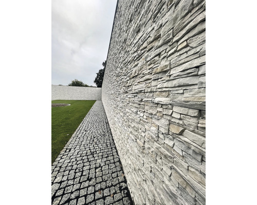 Venkovní fotografie zdi z přírodního kamene vedle cesty z dlažebních kostek