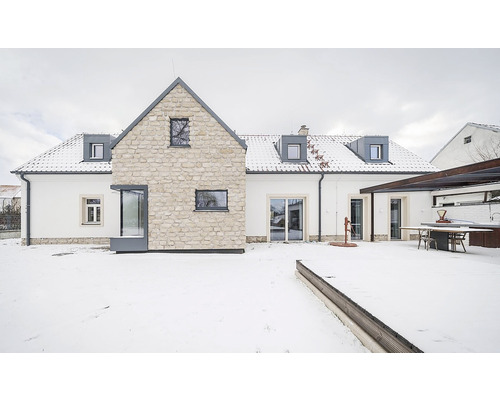 Venkovní pohled na dům s kamennou fasádou a zasněženou zahradou