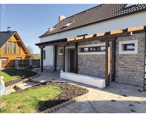 Fasáda domu s kamennou zdí, dřevěnou pergolou a dlážděnou terasou