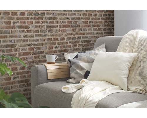 Obývací pokoj s pohovkou, polštáři, dekou a stěnou s cihlovým vzhledem