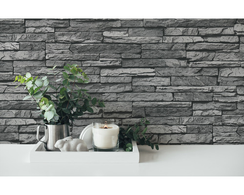 Dekorace stěny s tapetou imitující kámen, dekorace se svíčkou a zelenou rostlinou