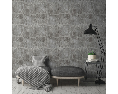 Šedá cihlová tapeta ve stylovém obývacím pokoji s lampou, taburetem a polštáři.