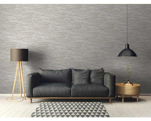 Obývací pokoj s pohovkou, stojací lampou a závěsným svítidlem před strukturovanou stěnou