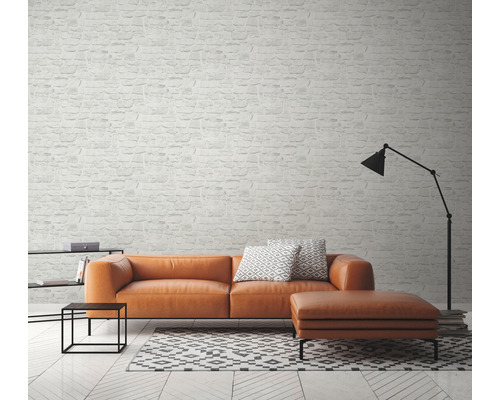 Obývací pokoj s pohovkou, stoličkou, lampou a tapetou se vzorem cihel