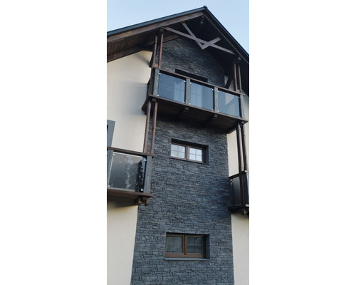 Fasáda domu s kamenným obkladem a balkony se skleněným zábradlím