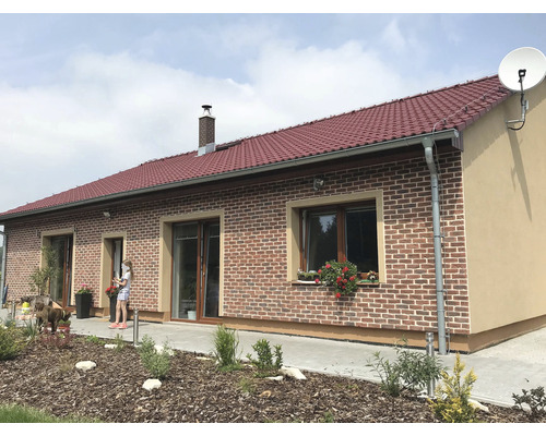 Rodinný dům s cihlovou střechou, zdobený cihlovým zdivem a satelitním přijímačem