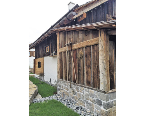 Fasáda dřevěného domu s kamennými prvky a zahradní úpravou