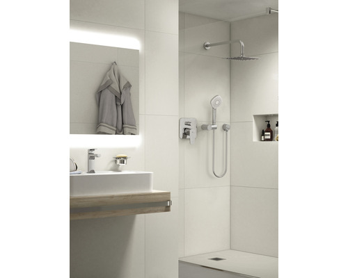 Světlá koupelna s umyvadlem, zrcadlem, ručníkem a sprchou