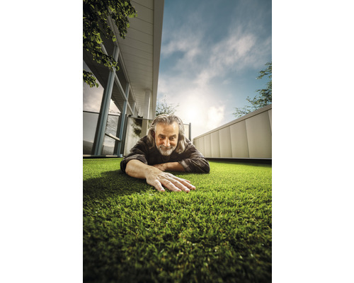 Muž leží na umělém trávníku před domem.