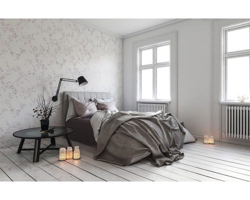 Ložnice s postelí, nočním stolkem a květinovou tapetou