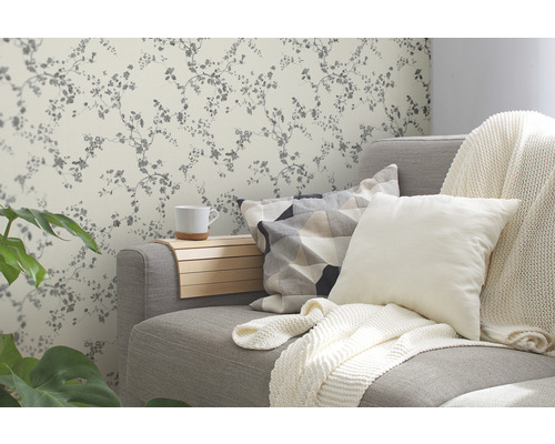 Obývací pokoj s šedou pohovkou, polštáři a květinovou tapetou