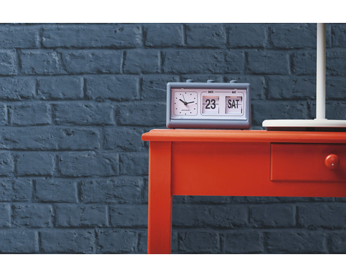 Stůl s překlápěcím budíkem před cihlovou zdí