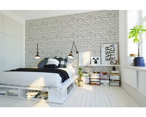 Ložnice s postelí, nočním stolkem a tapetou s cihlovým vzorem