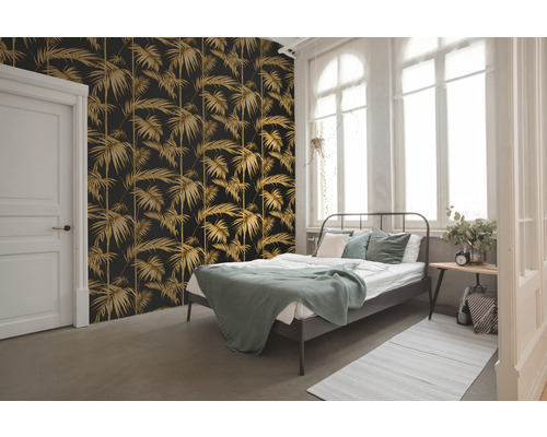 Ložnice s tapetou s palmovým vzorem, postelí a bílými okny.
