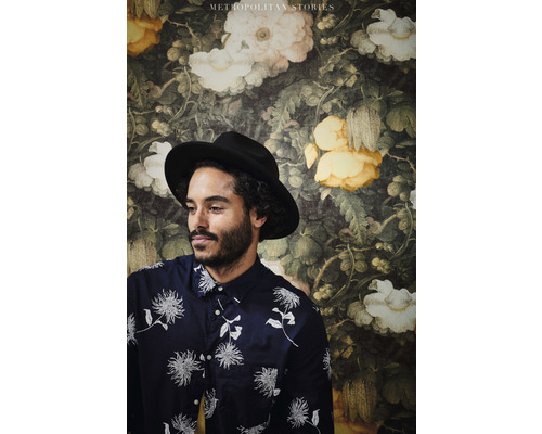 Muž s kloboukem před květinovou tapetou z kolekce Metropolitan Stories.